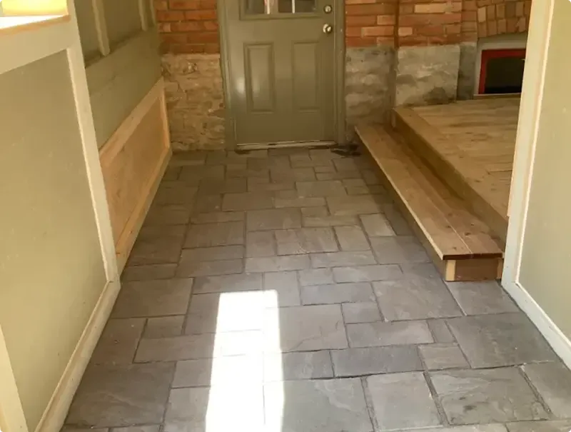 Interlocking paver landing at a back entrance beside a cedar step